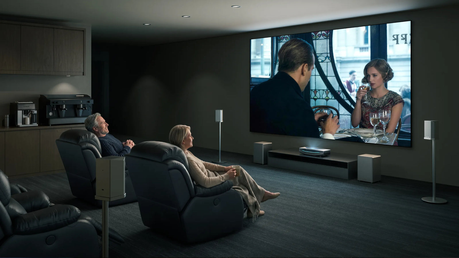 Couple watching a film in a private home cinema with an AWOL Vision projector, large screen and surround speakers.